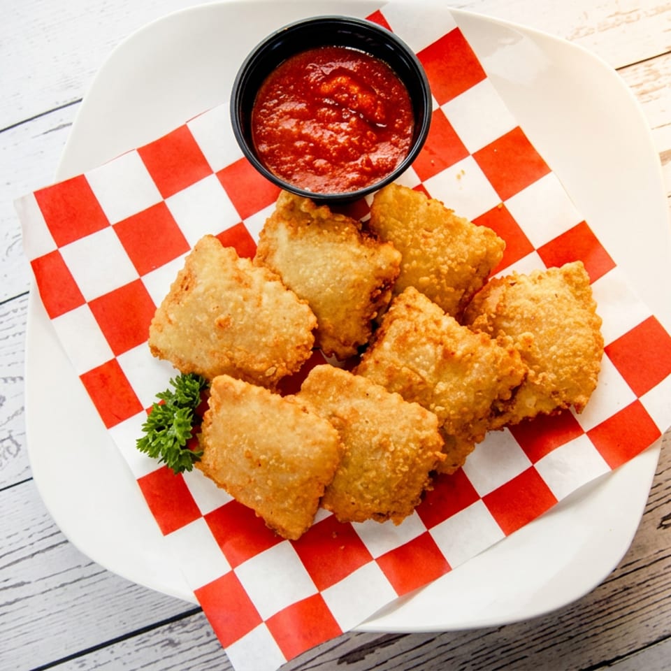 Golden fried ravioli served on red-and-white checkered paper with marinara dipping sauce and parsley garnish.